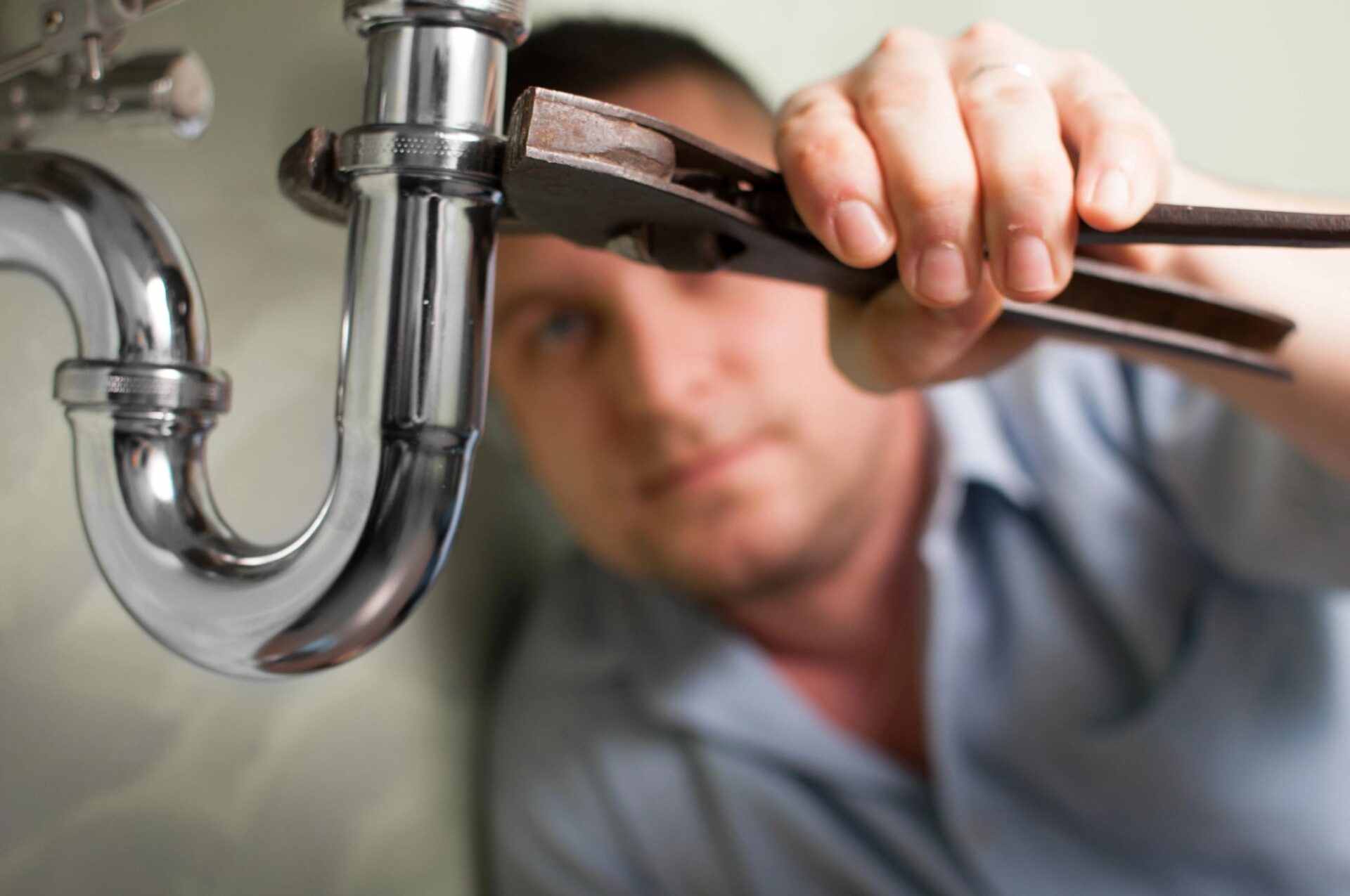 A man is fixing the faucet of his sink.