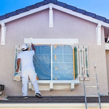 A man painting the outside of a house.