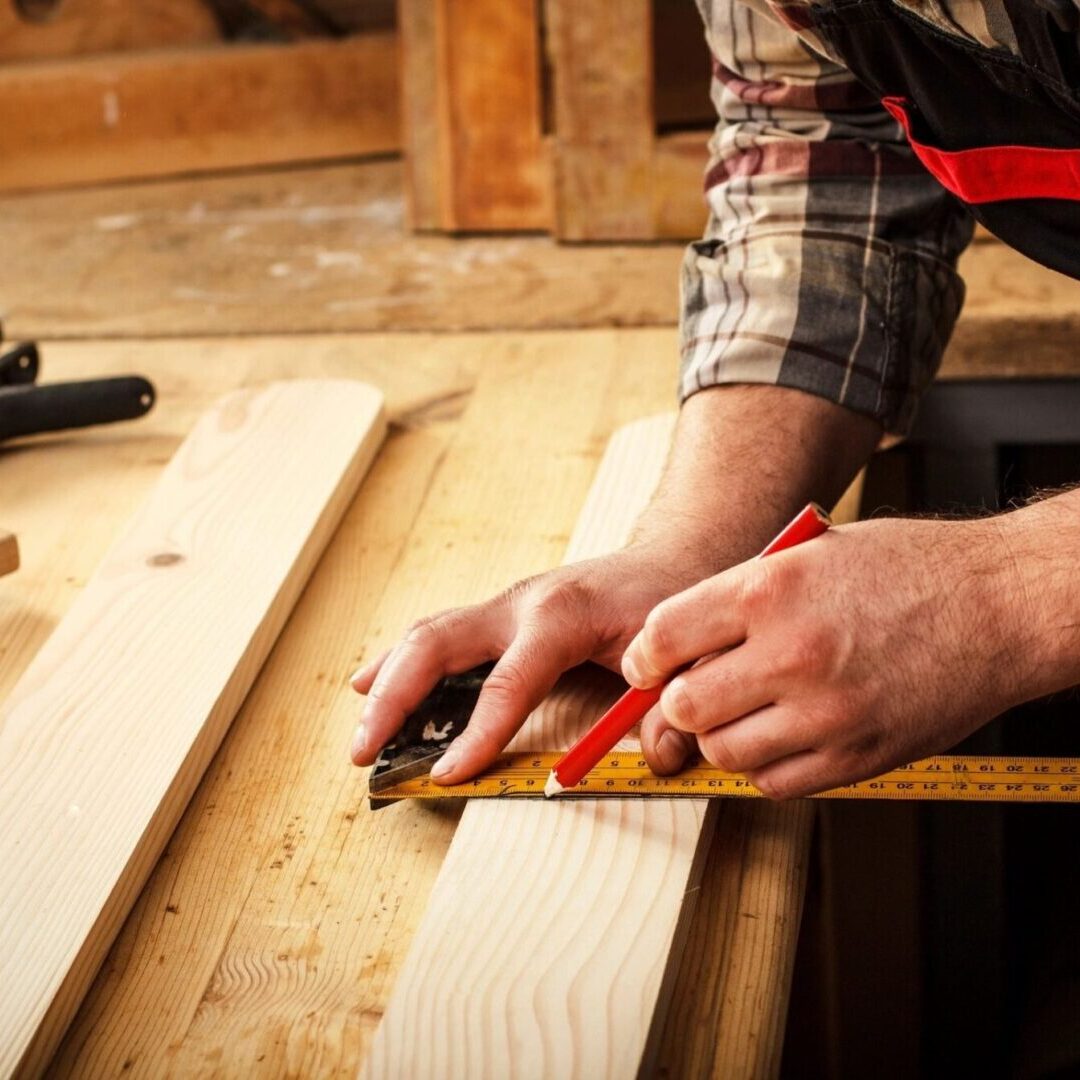 A person using a pair of scissors to cut wood.