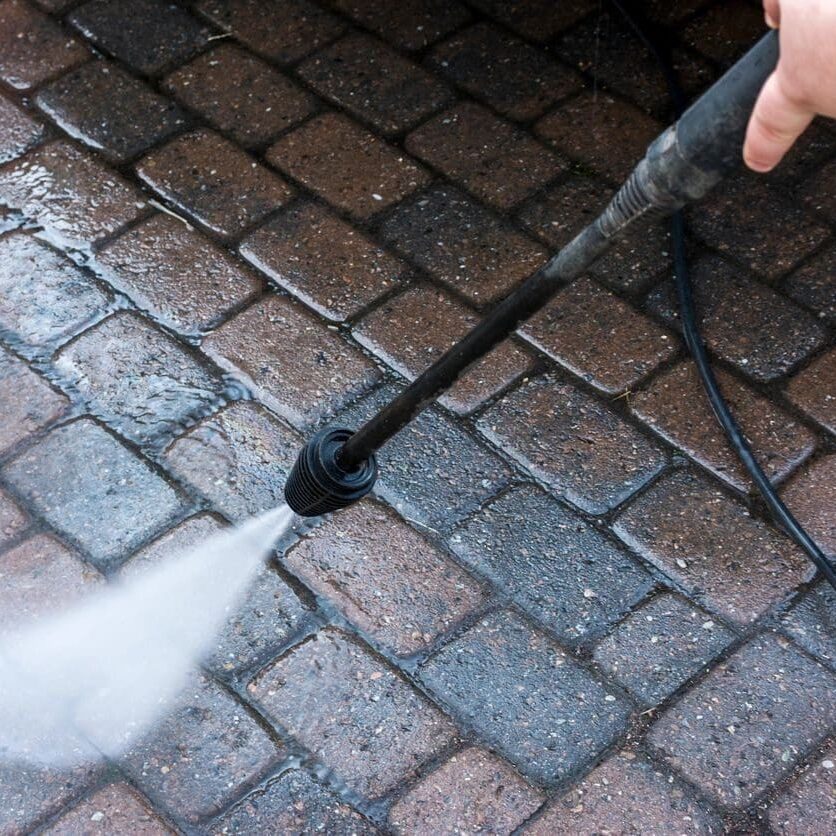 A person using a hose to clean the floor.